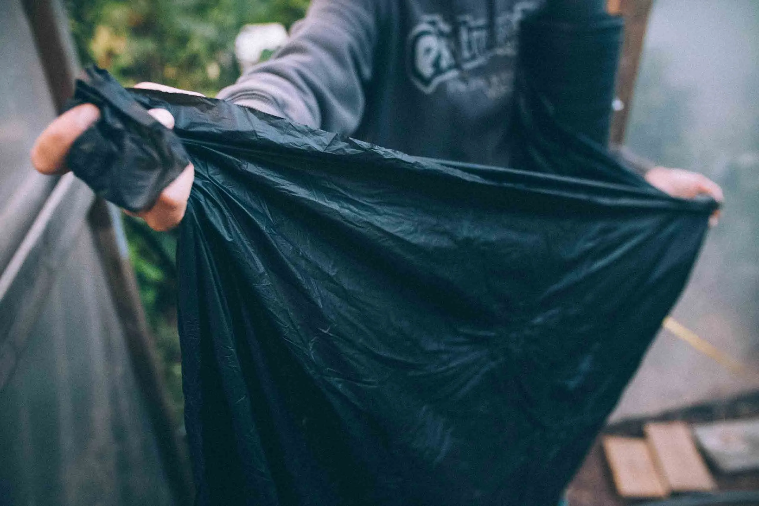 Person håller upp en svart komposterbar marktäckningsduk med båda händerna.