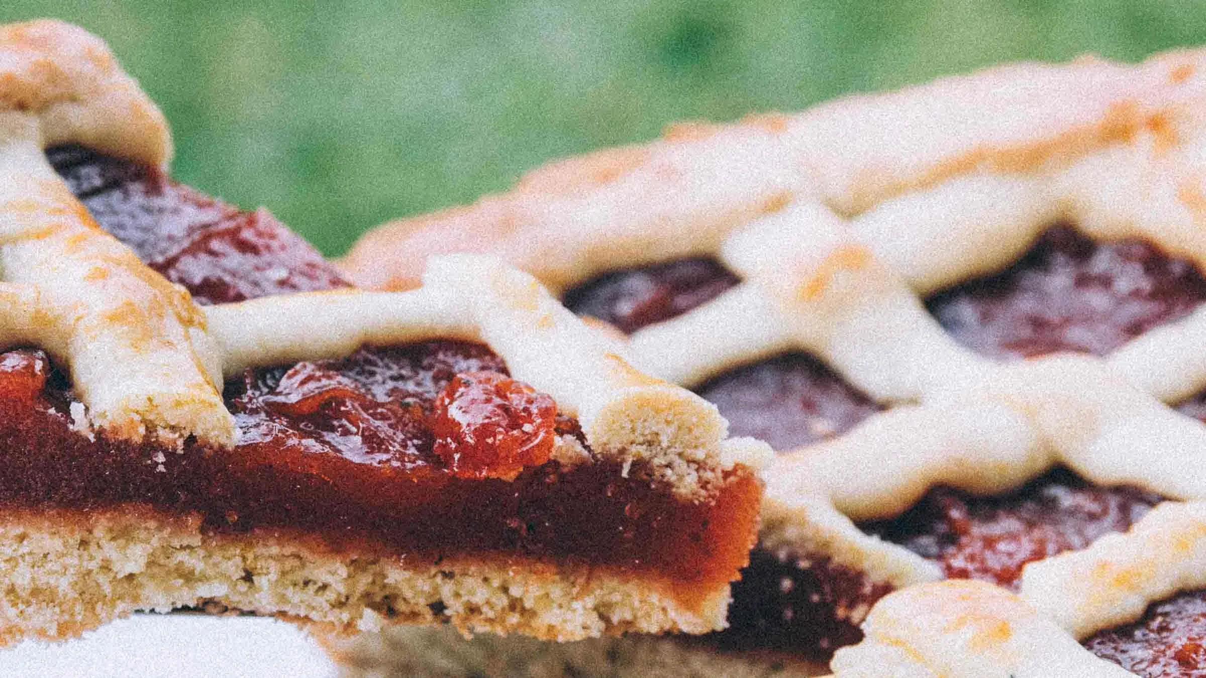 Kvittenpaj visar en närbild på en saftig pajbit med kvittenmarmelad, lyft från en gyllenbrun paj med dekorativt galler av mördeg.